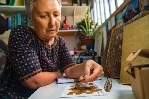 Radio Jai -La experta en monedas Gabriela Bijovsky examina las monedas de oro encontradas en el sitio arqueológico de Bania. (Yaniv Berman/Autoridad de Antigüedades de Israel)